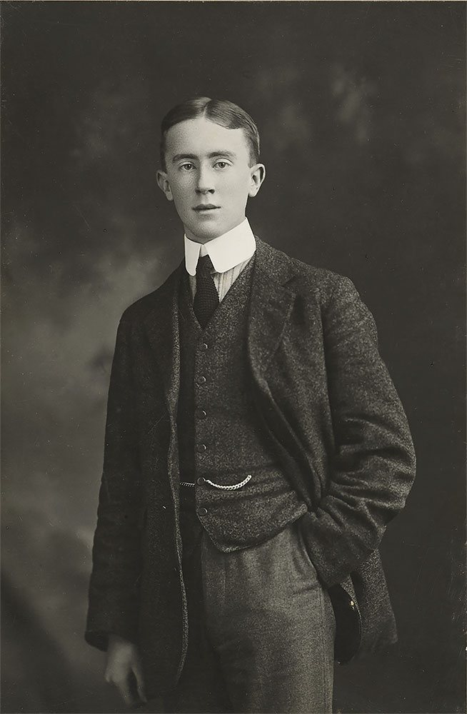 Studio portrait of the young J.R.R. Tolkien standing in a tweed three-piece suit, 1911