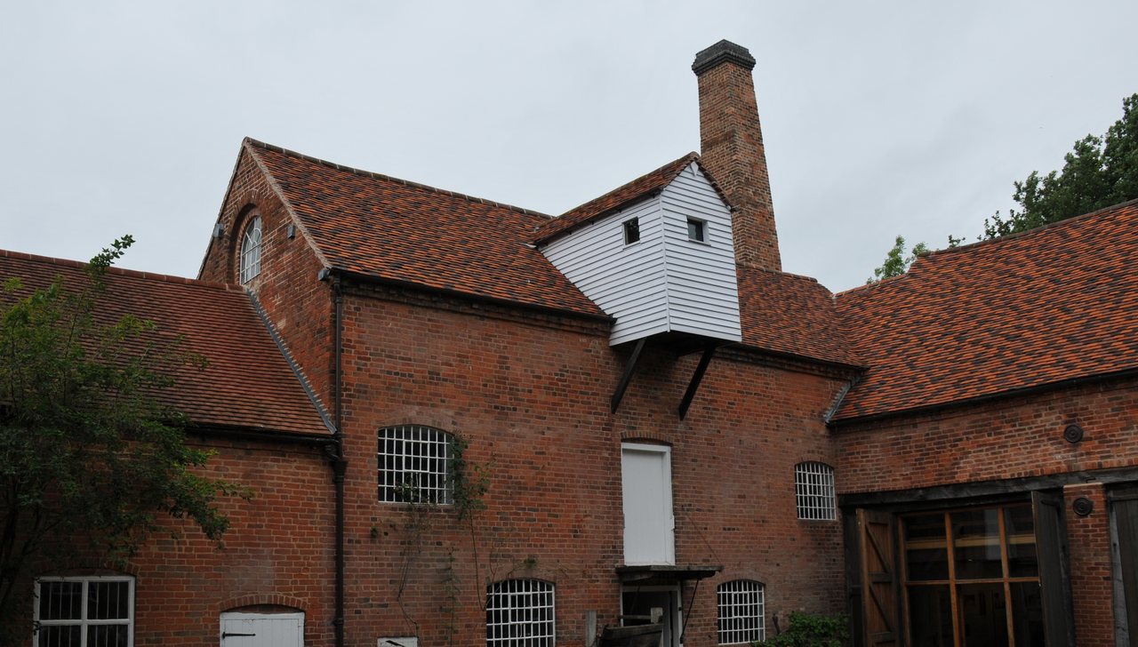 Sarehole Mill: red-brick mill buildings with a tall chimney and a white weatherboarded hoist housing under an overcast sky